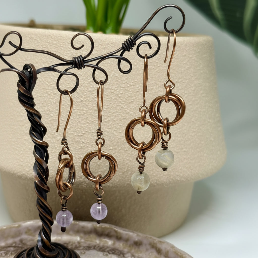 Pair of copper and gemstone bead earrings on a decorative stand with a plant in the background.