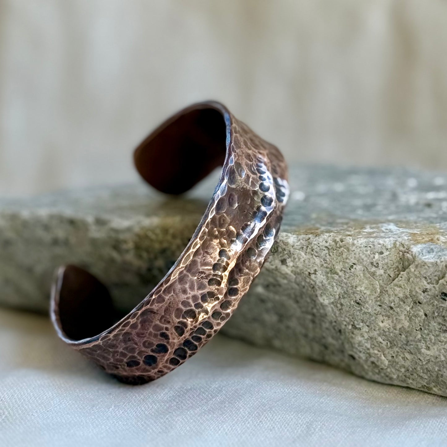 Hammered copper bracelet on a textured surface