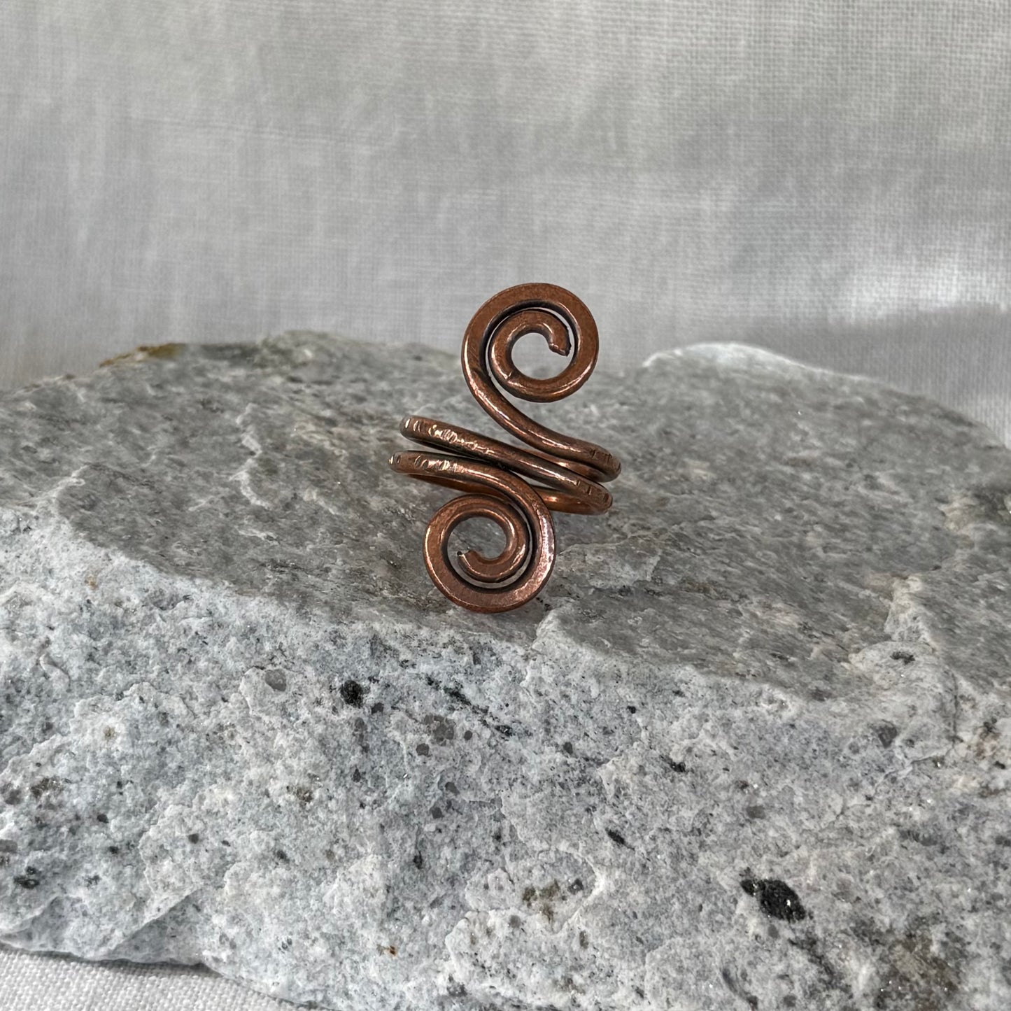 Copper Spiral Ring on a stone surface with linen background
