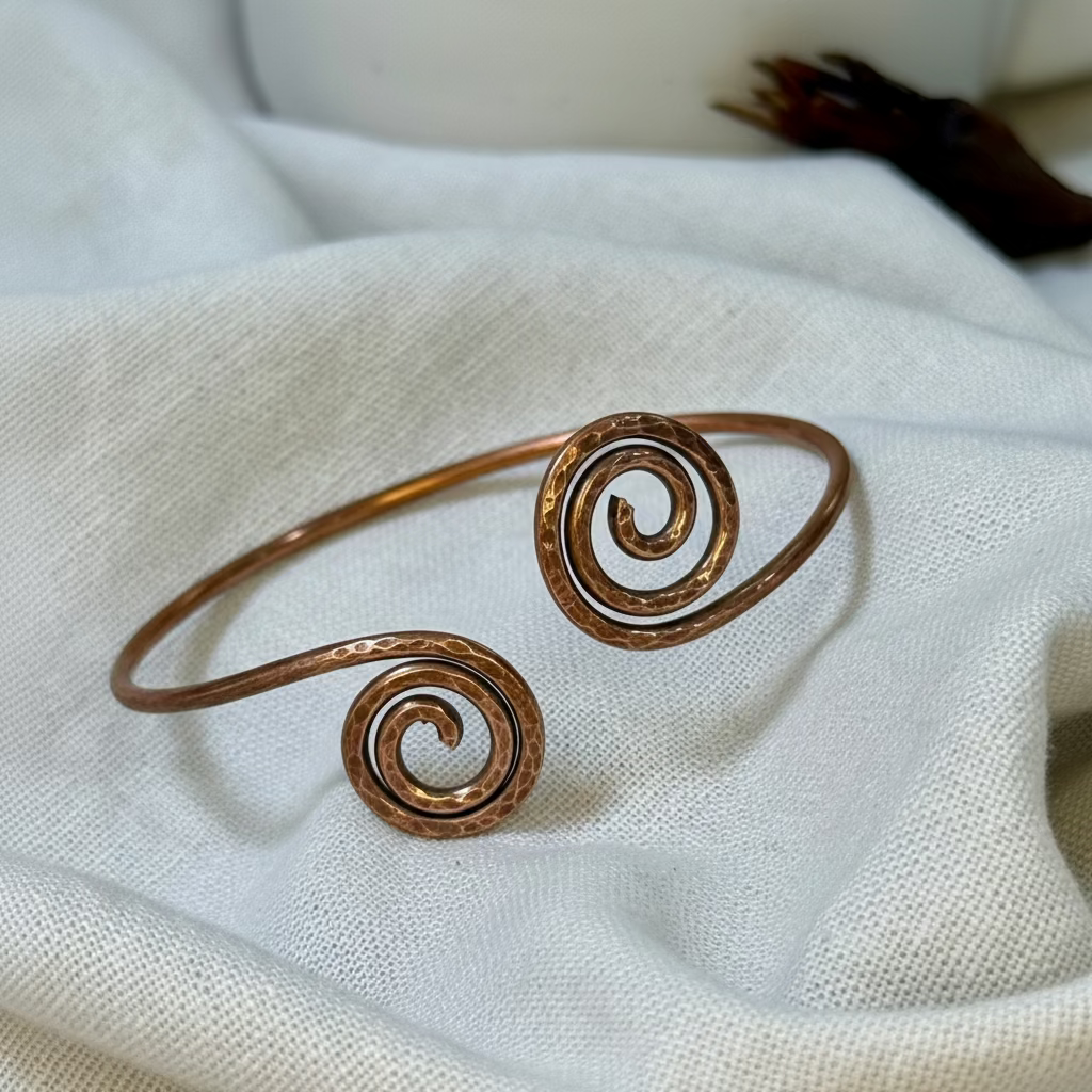 Copper bangle with spiral design on a linen background
