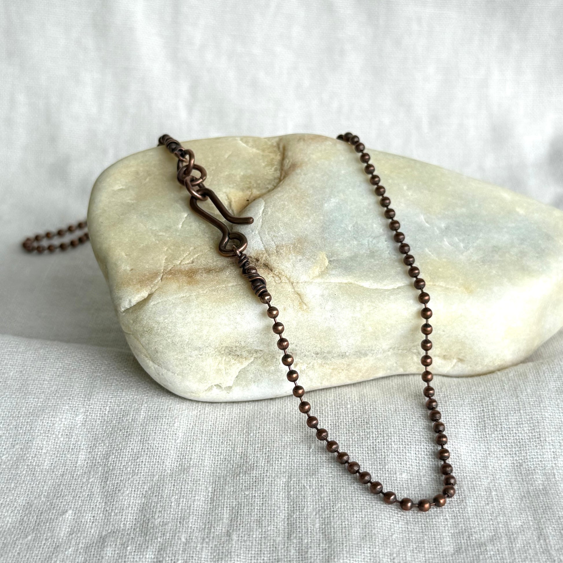 Copper necklace ball chain on a stone surface on line background