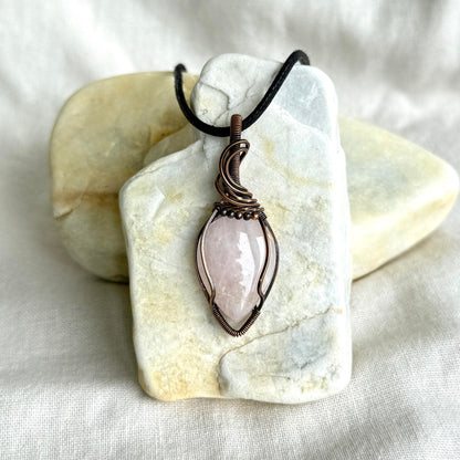 Copper pendant with a black cord on a piece of stone on linen background