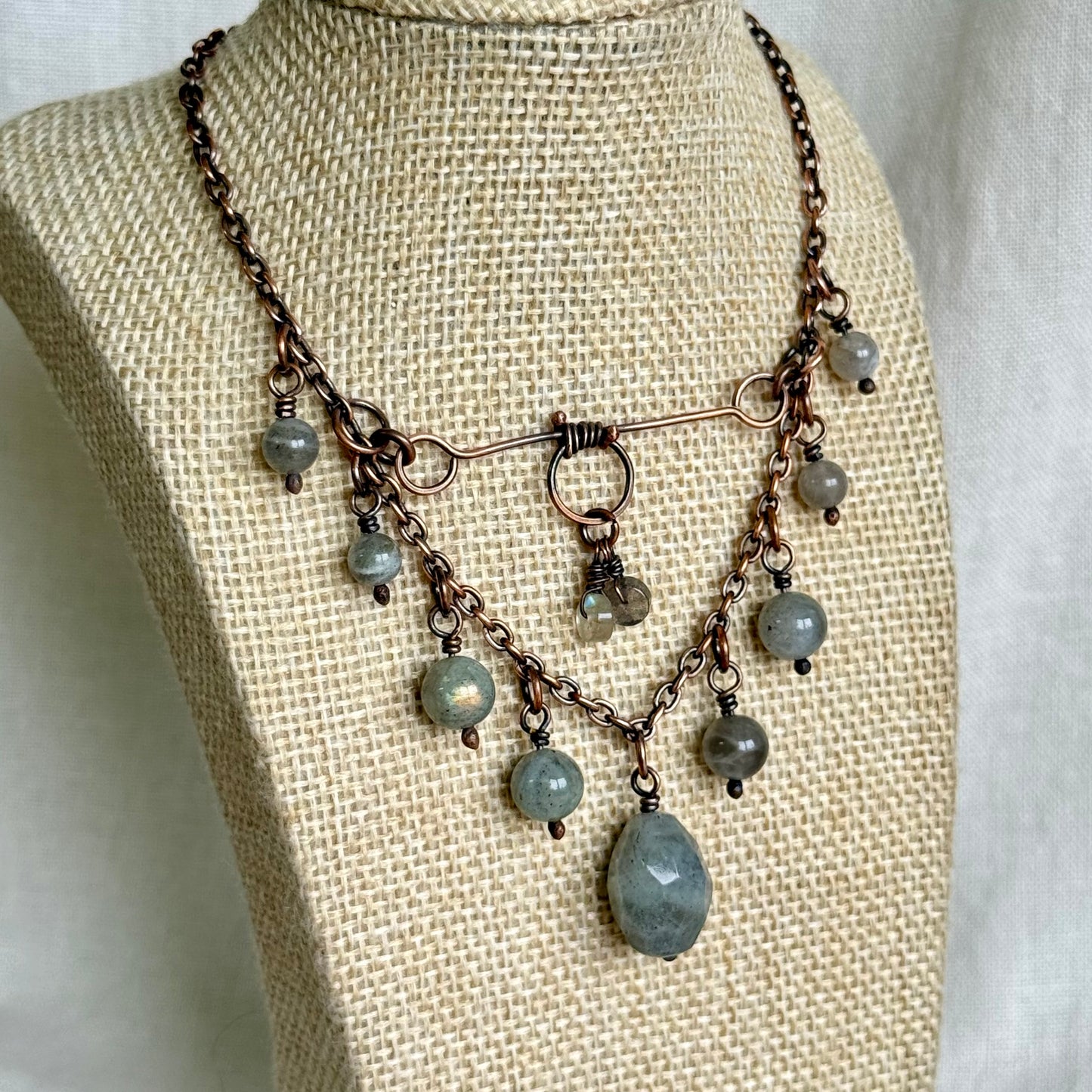 Necklace with gray beads on a mannequin bust against a neutral background