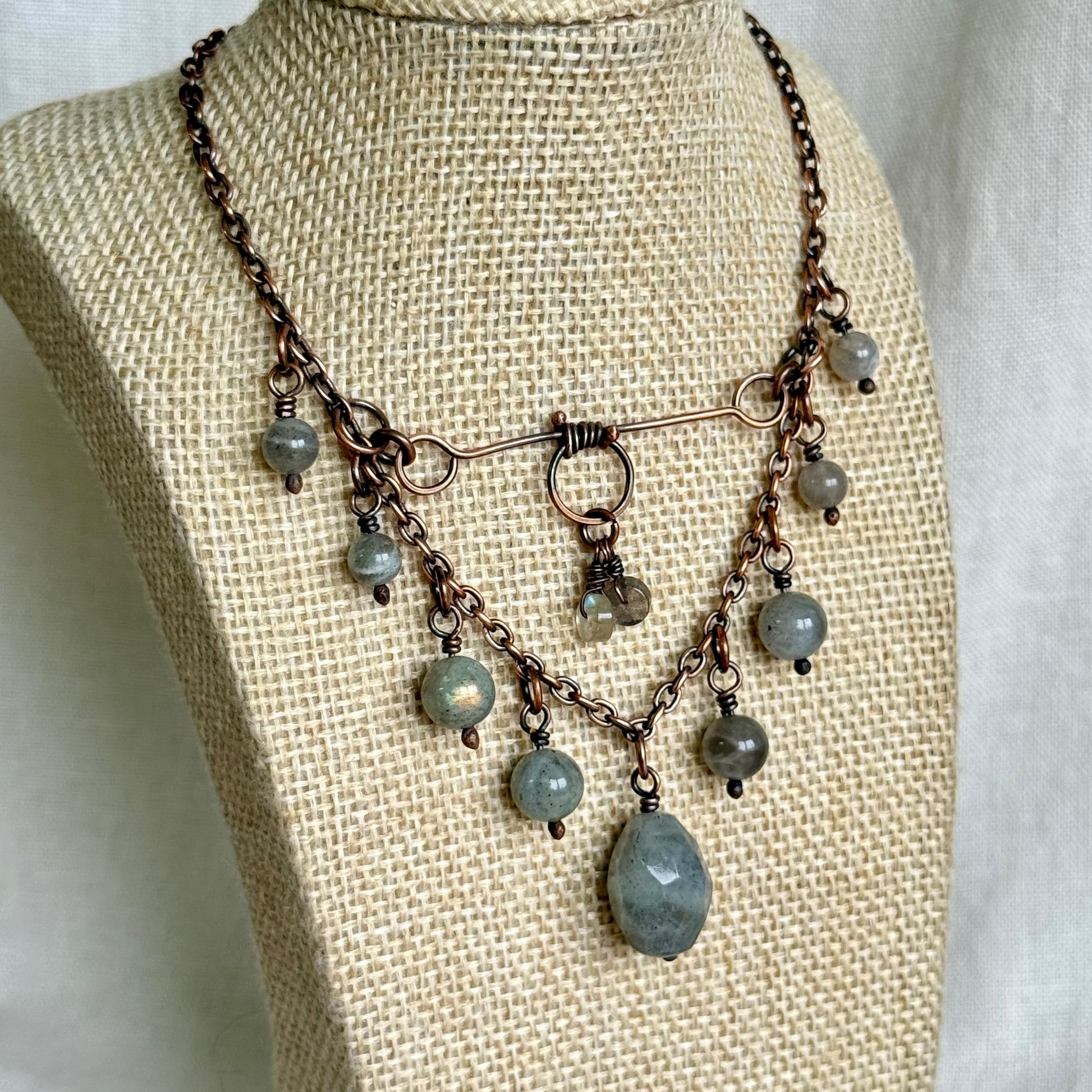 Necklace with gray beads on a mannequin bust against a neutral background