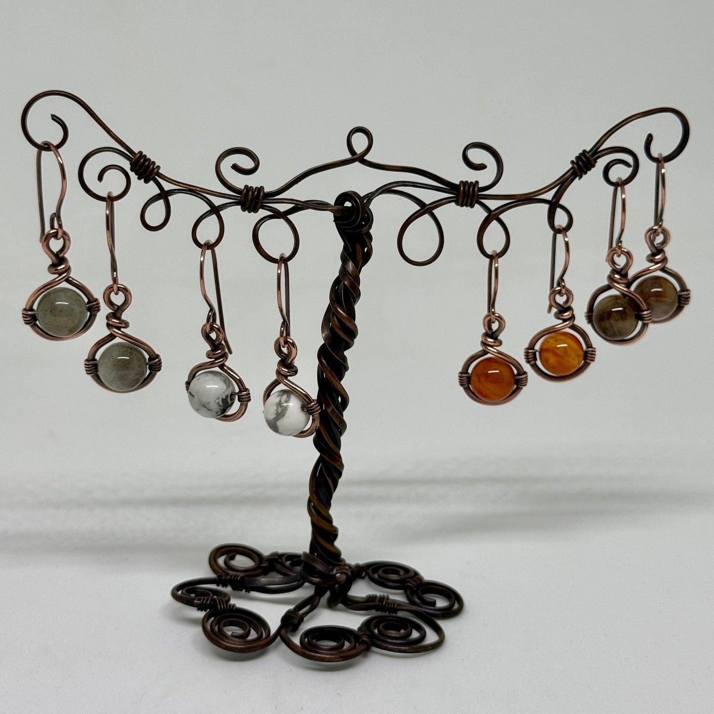 decorative copper earring stand with hanging copper  earrings with gemstone beads on a white background