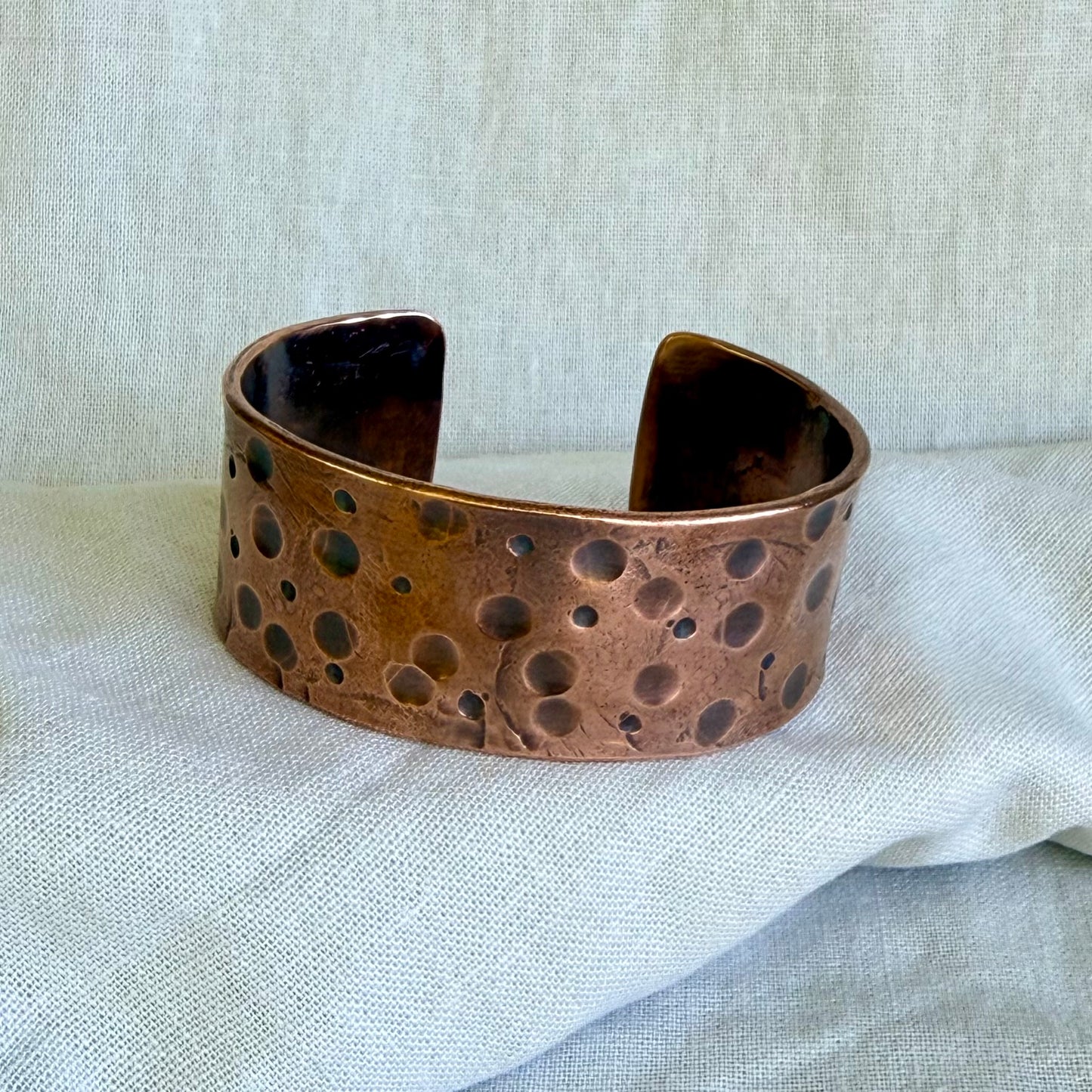 Copper cuff bracelet on a textured fabric background