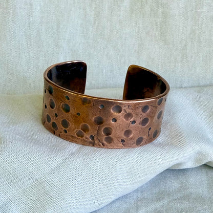 Copper cuff bracelet on a textured fabric background