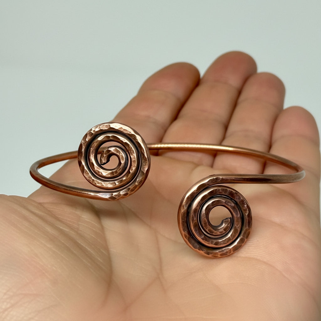 Copper spiral bangle on a hand against a light background