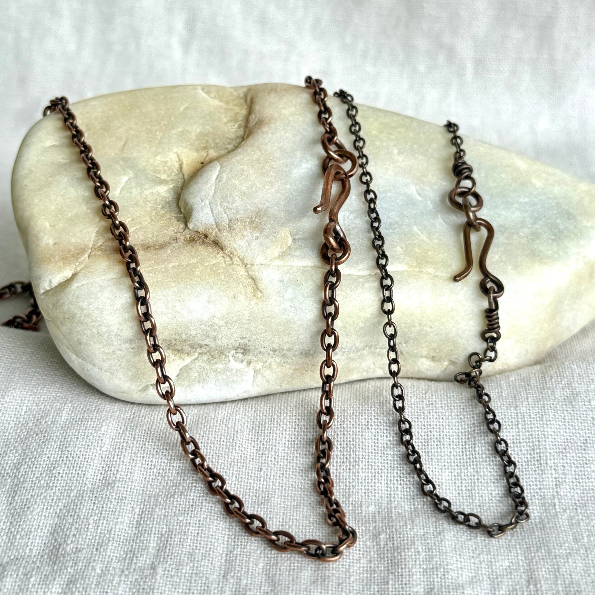 Two Copper necklace chains on a stone surface on line background