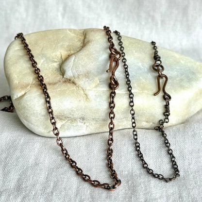 Two Copper necklace chains on a stone surface on line background