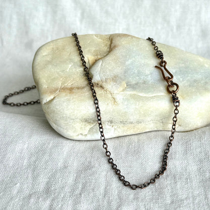 Copper necklace chain on a stone surface on line background