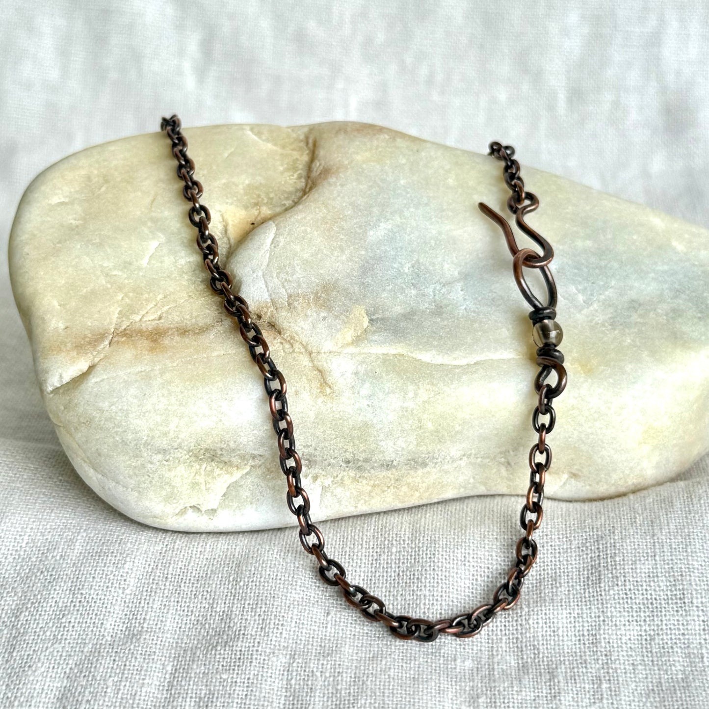 Copper necklace chain on a stone surface on line background
