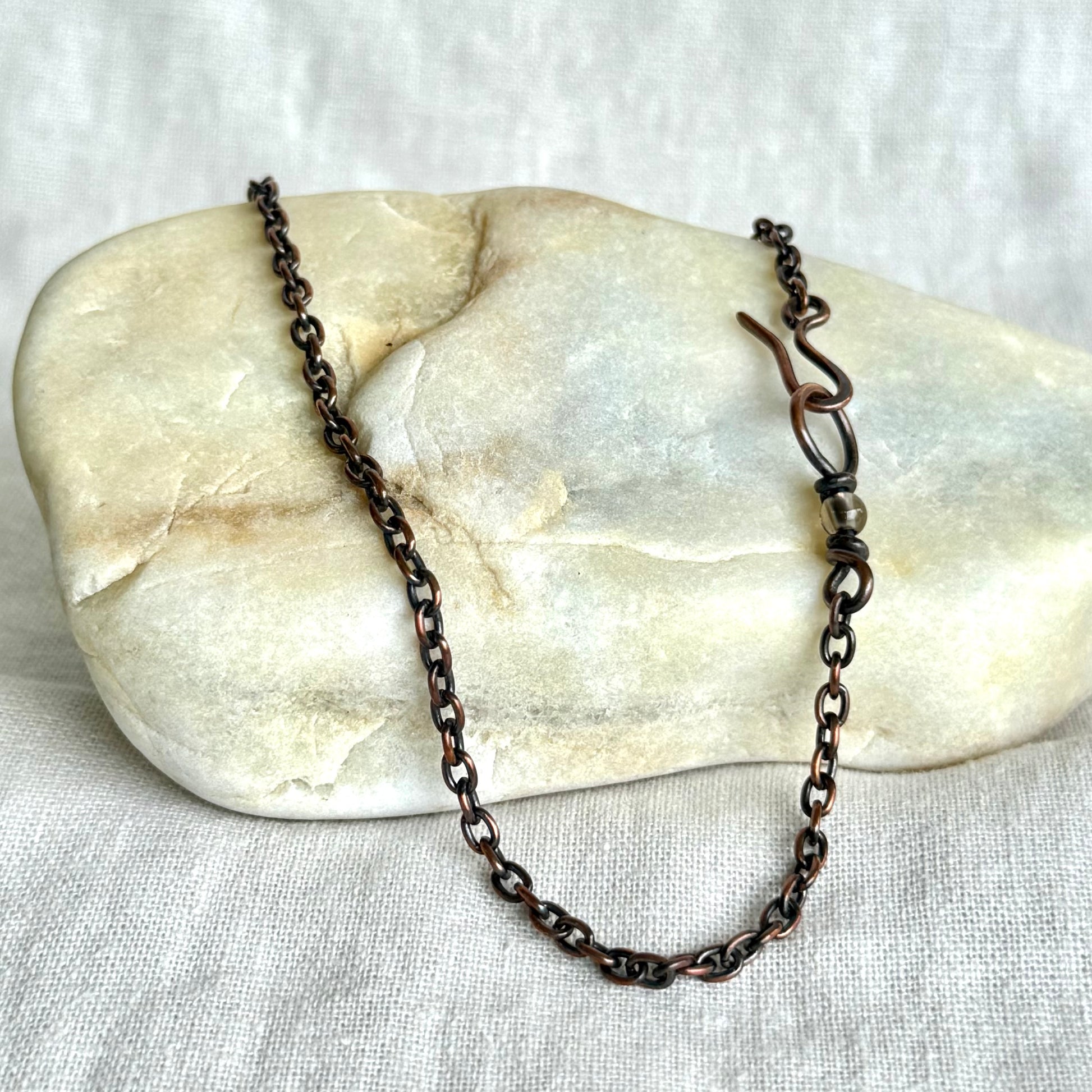 Copper necklace chain on a stone surface on line background