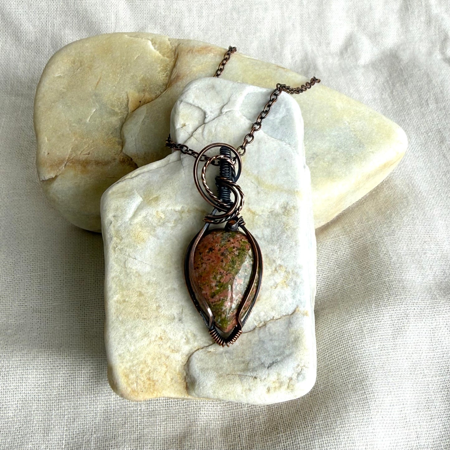 Copper pendant on  a piece of stone on linen background