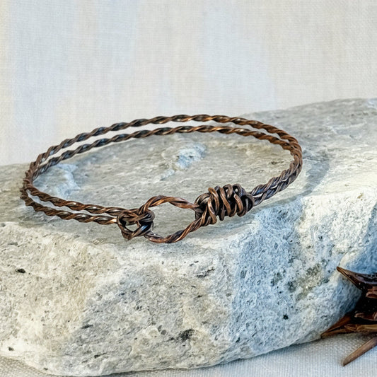 Copper bracelet on a stone surface with linen background