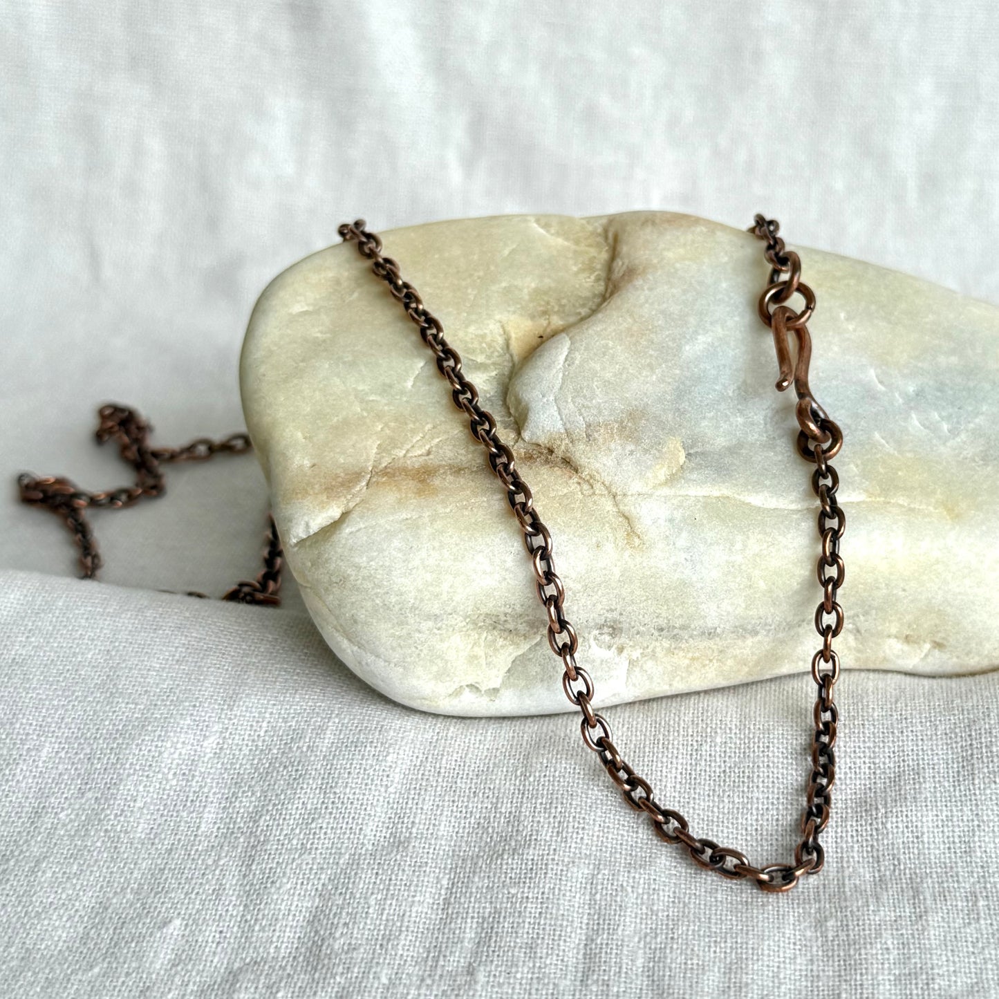 Copper necklace chain on a stone surface on line background