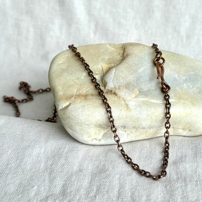 Copper necklace chain on a stone surface on line background