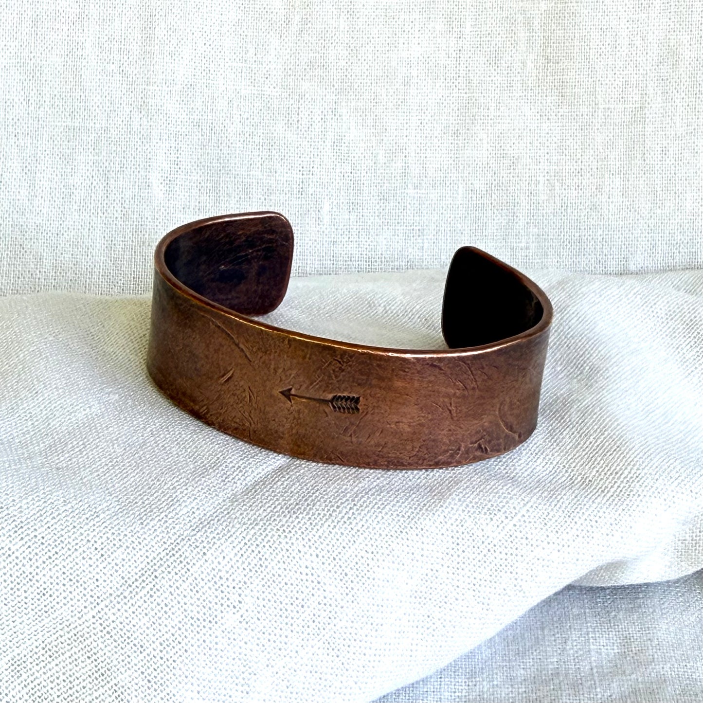 Copper cuff bracelet on a white fabric background