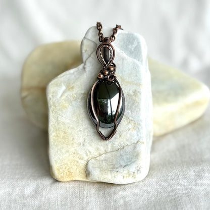 Copper pendant with a hematite stone on a piece of stone on linen background
