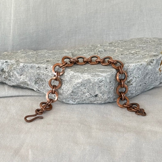 Copper chain bracelet on a stone surface with a neutral background