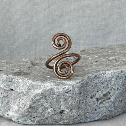 Copper spiral ring on a stone surface with a linen fabric background