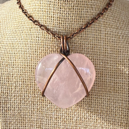 Necklace with a heart-shaped pink stone pendant on a textured beige background