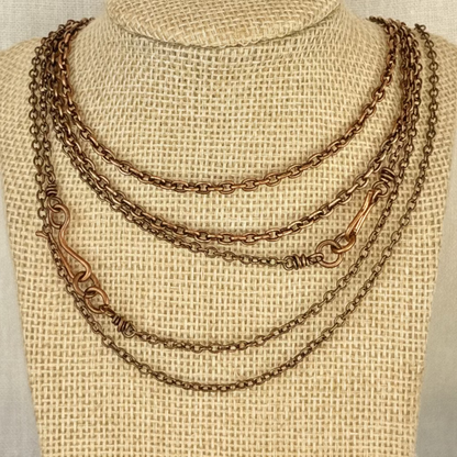 set of copper chains on a woven fabric necklace display bust with linen background
