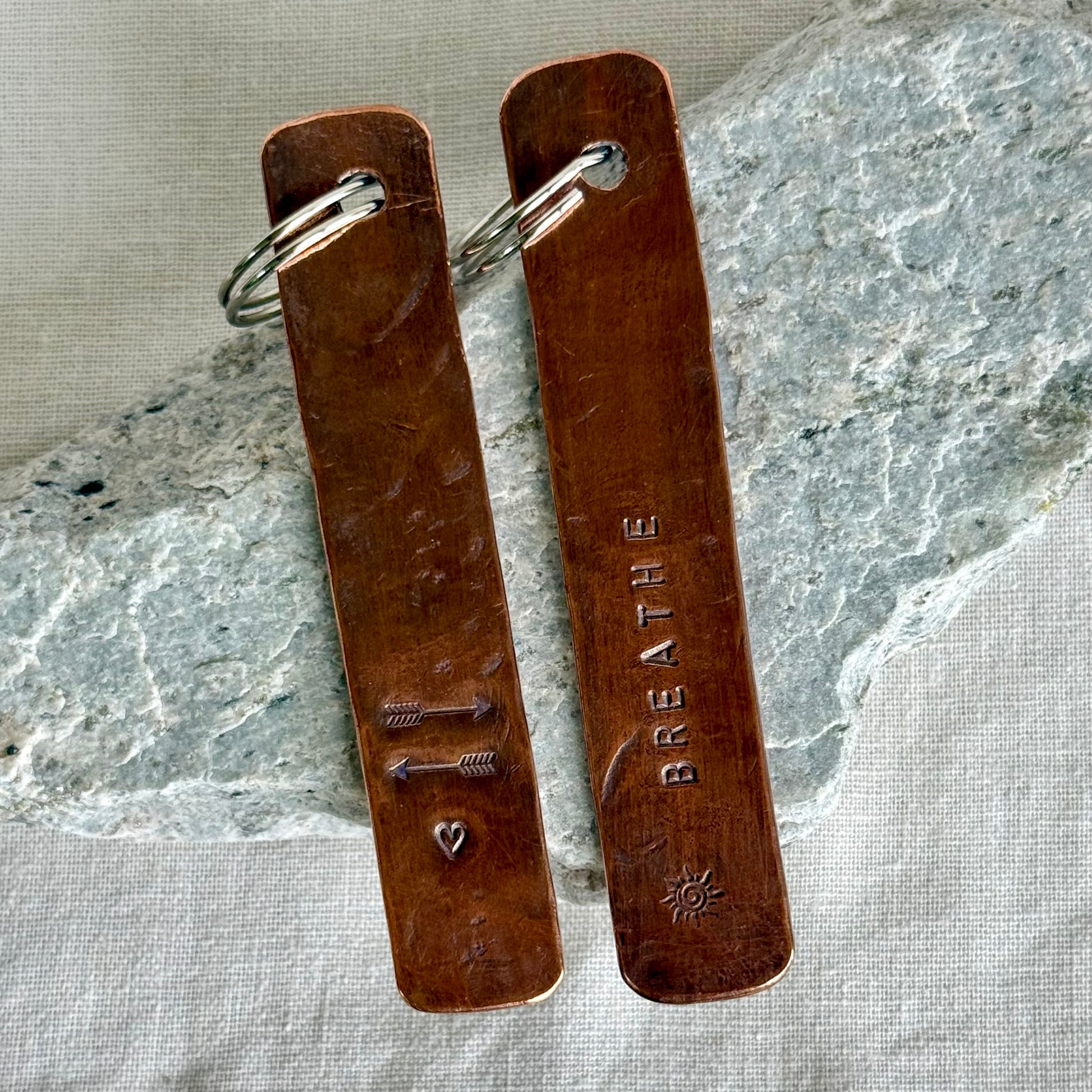 Two copper  keychain against a stone and linen background