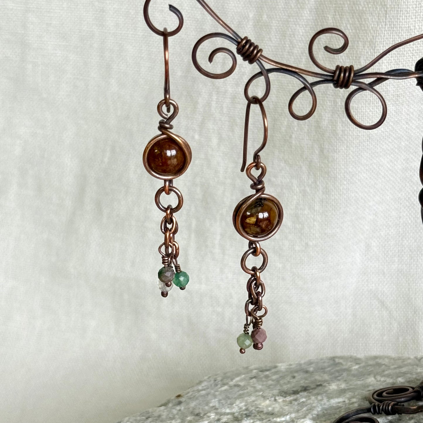 Pair of copper earrings with beads on a textured white background