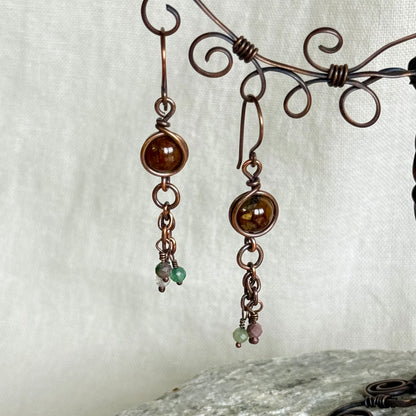 Pair of copper earrings with beads on a textured white background