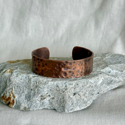 Copper bracelet on a textured stone surface with a neutral background