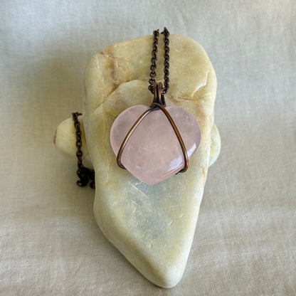 Copper Necklace with a pink rose quartz pendant on a stone surface