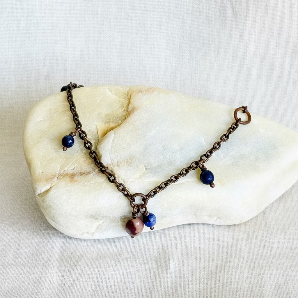 copper chain anklet with beads on a stone surface