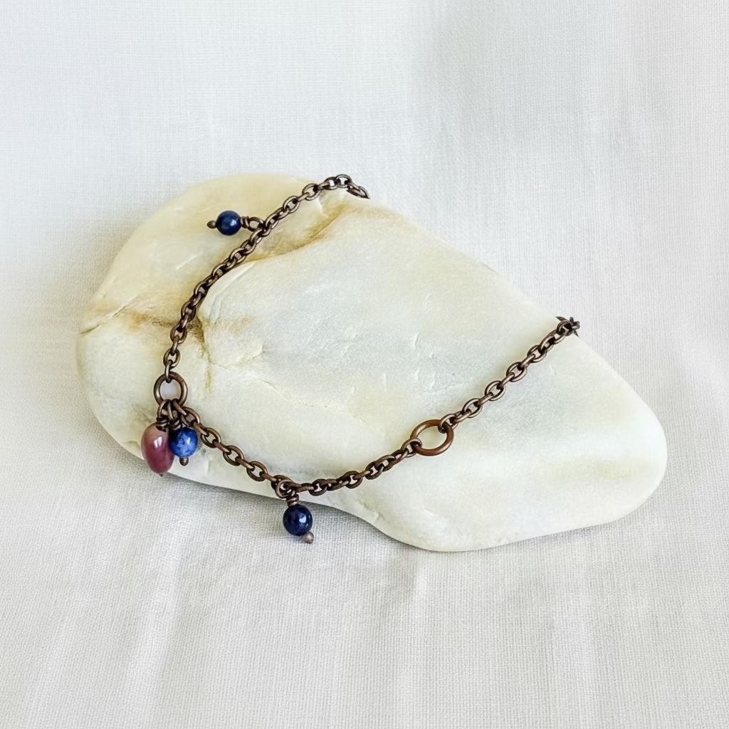 copper chain anklet with beads on a stone surface