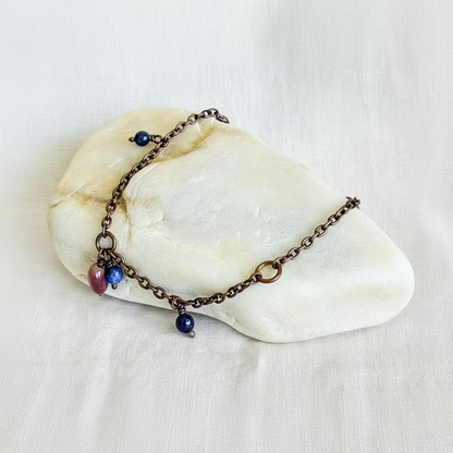 copper chain anklet with beads on a stone surface