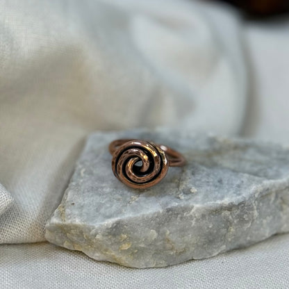 Copper spiral ring on a white grey stone with linen fabric background