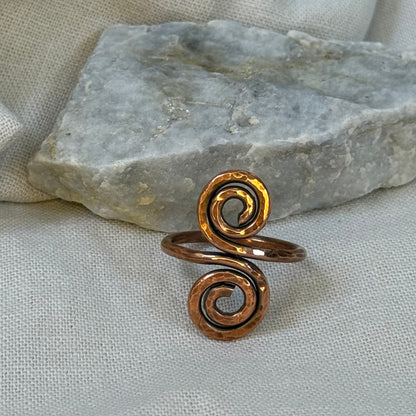 Copper spiral ring on a stone surface with linen background