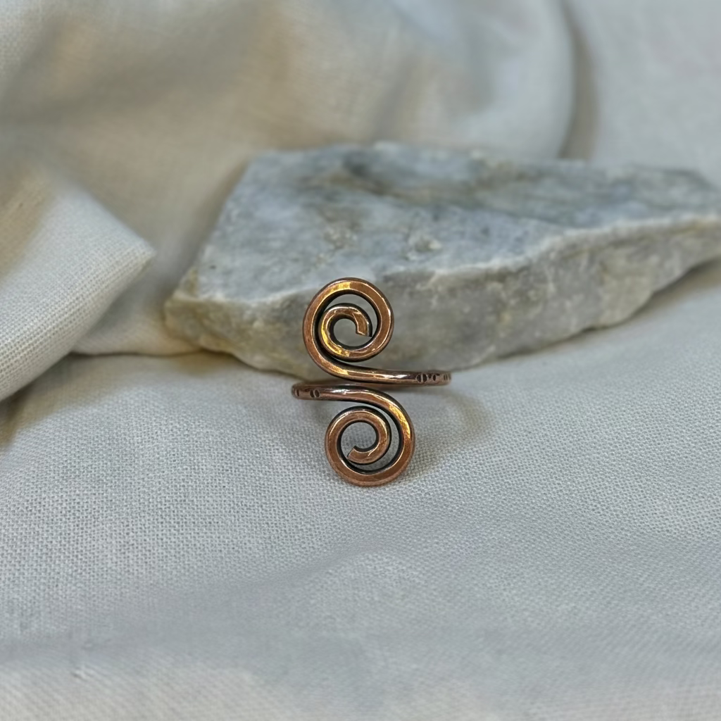 Copper spiral ring on a stone surface with linen background