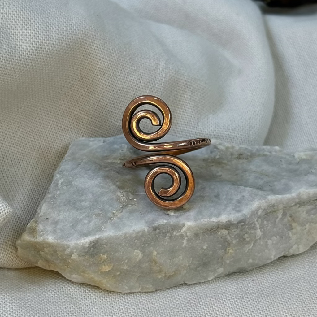 Copper spiral ring on a stone surface with linen background