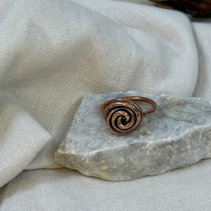 Copper spiral ring on a white grey stone with linen fabric background