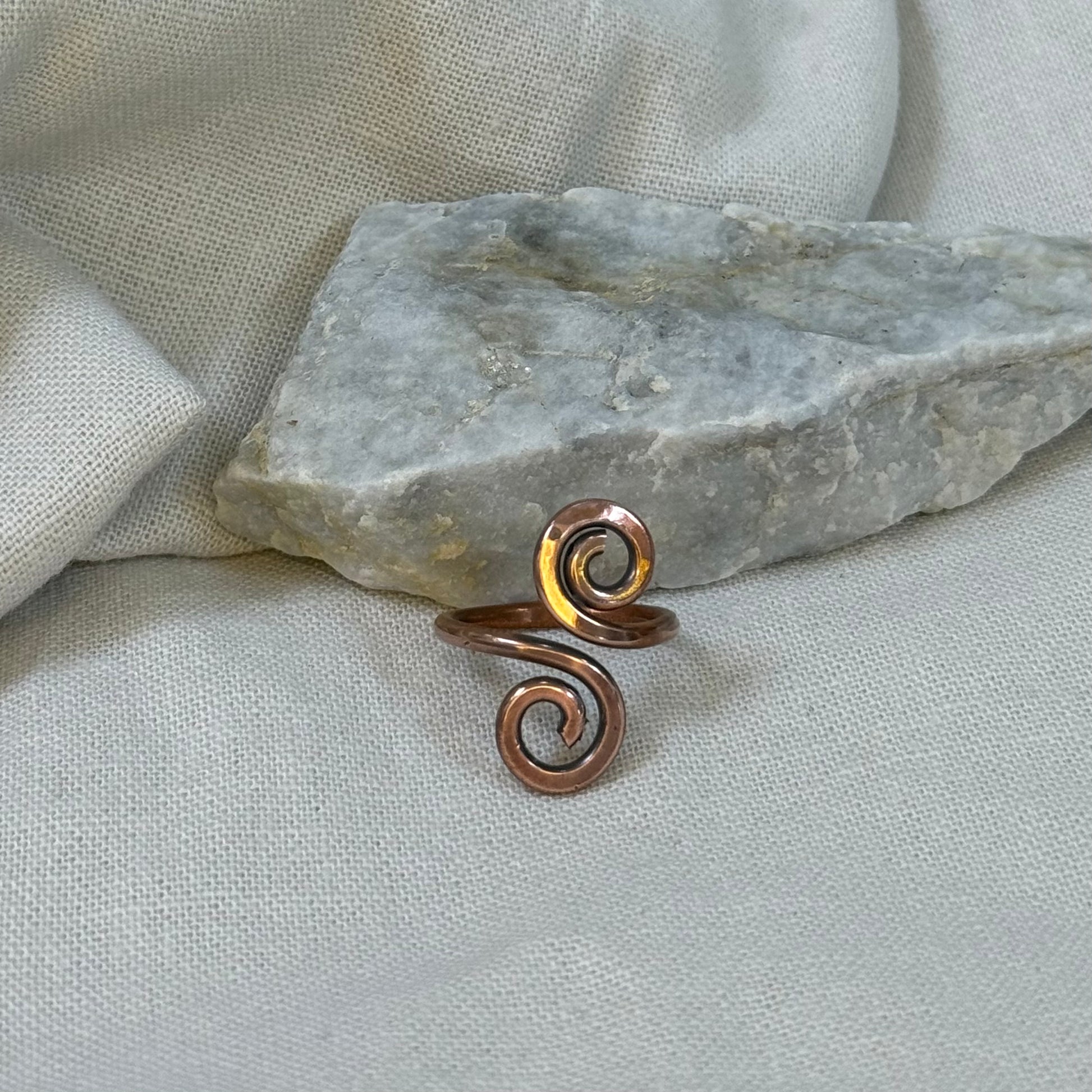 Copper spiral ring on a stone surface with linen background