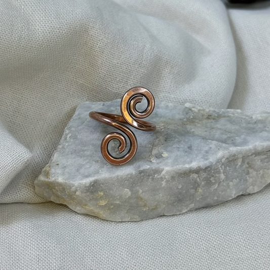 Copper spiral ring on a stone surface with linen background