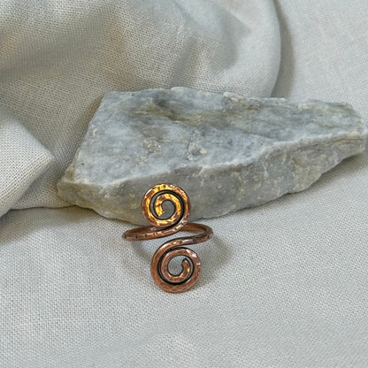 Copper spiral ring on a stone surface with linen background
