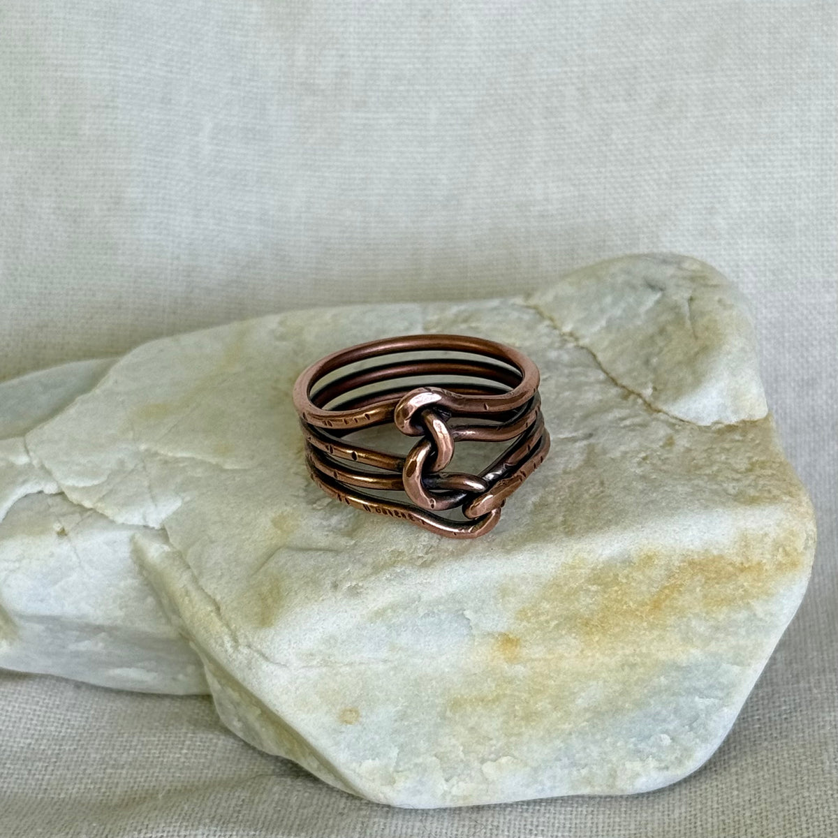 Wire wrapped copper ring on a piece of stone with a neutral background