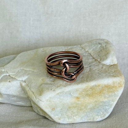 Wire wrapped copper ring on a piece of stone with a neutral background