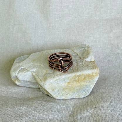 Copper wire ring on a white stone with a light background
